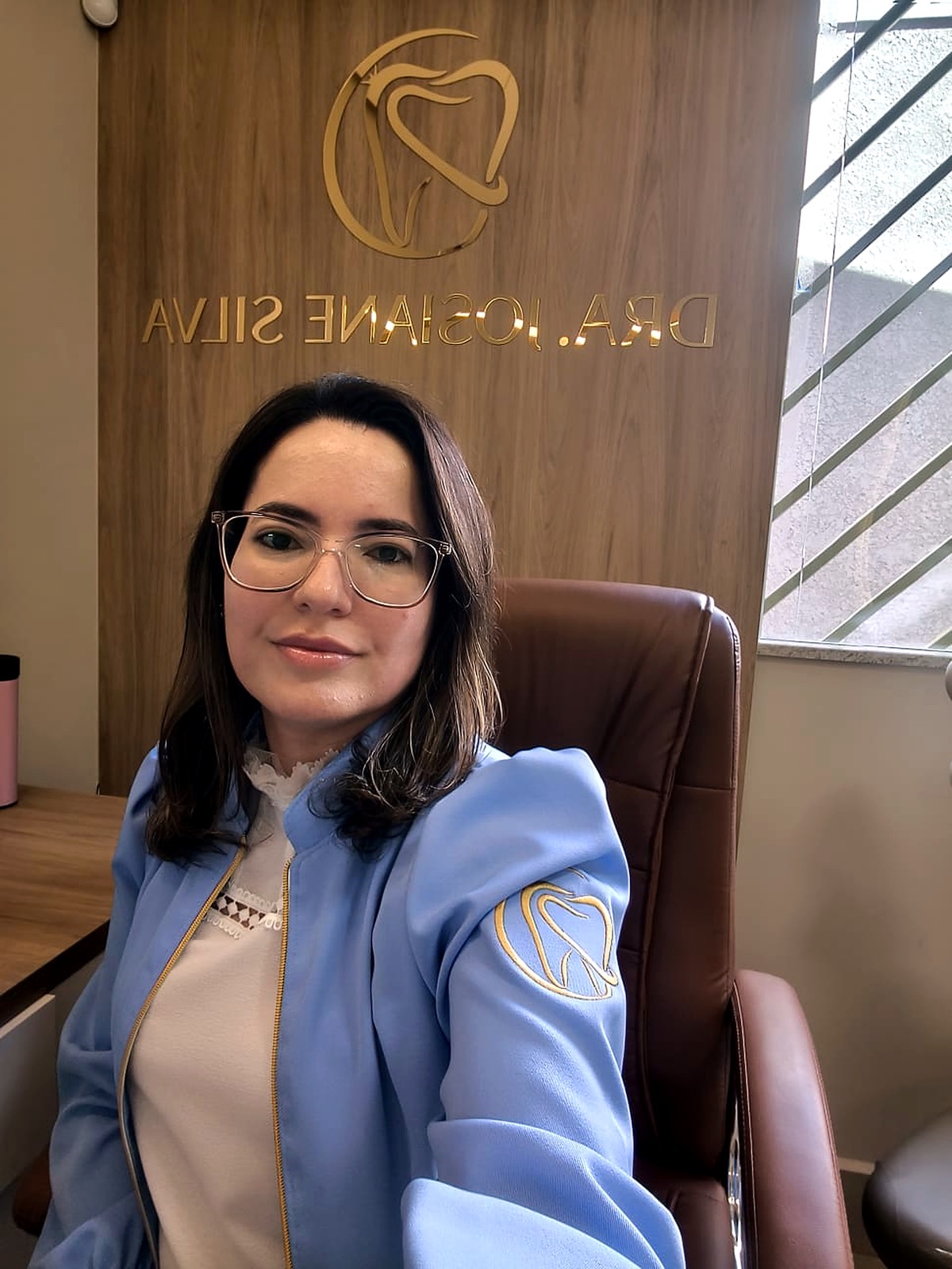 Dra. Josiane sentada em seu consultório odontológico