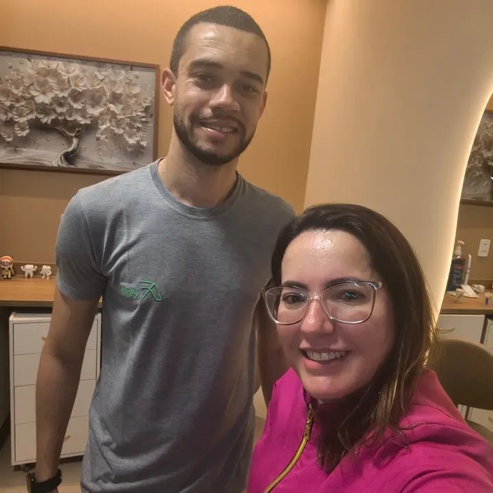 Dra. Josiane em sua sala de atendimento, com o logotipo ao fundo